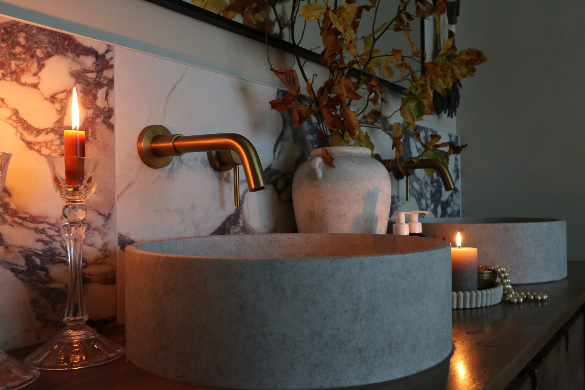 Candles in cut-glass holders, a stone vessel basin and a brass wall tap