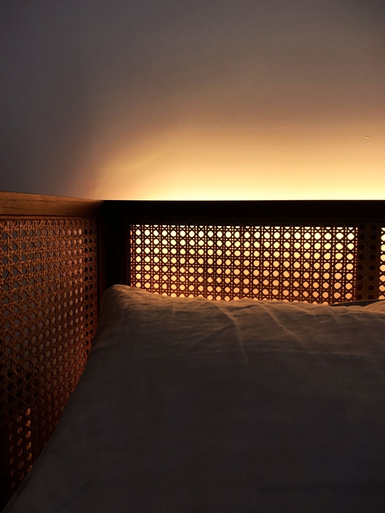 Close view of a cane headboard glowing from a hidden light strip