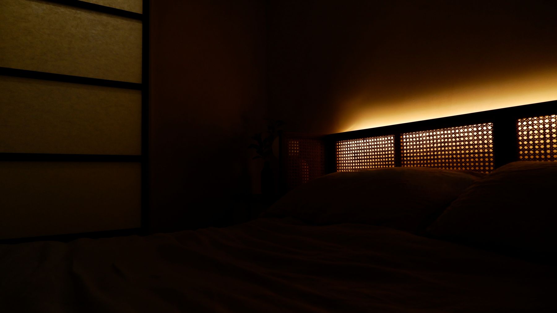 The bedroom at night with cane panels and the lit headboard