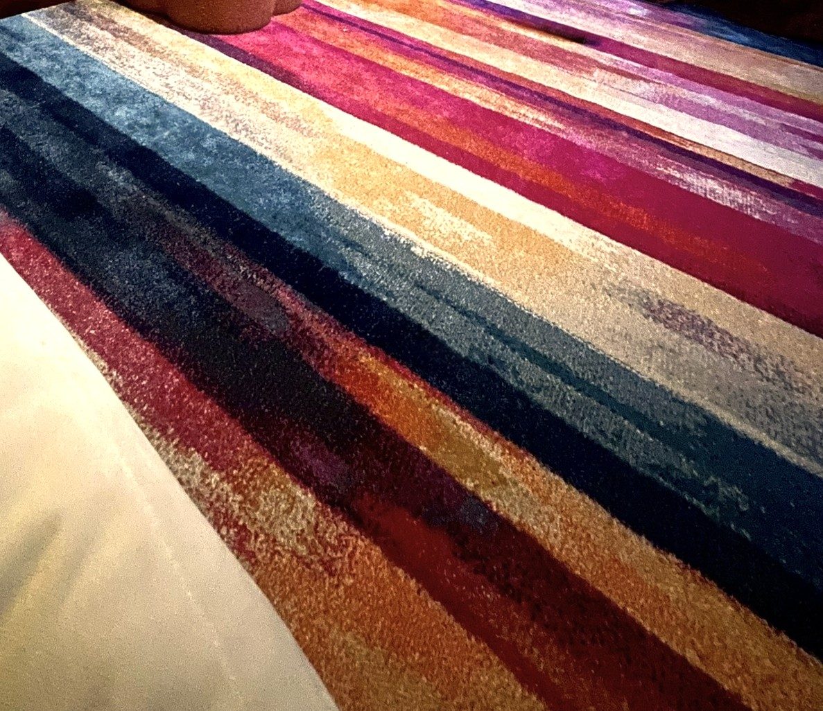 Close-up of a striped rug in berry, ochre, teal and cream