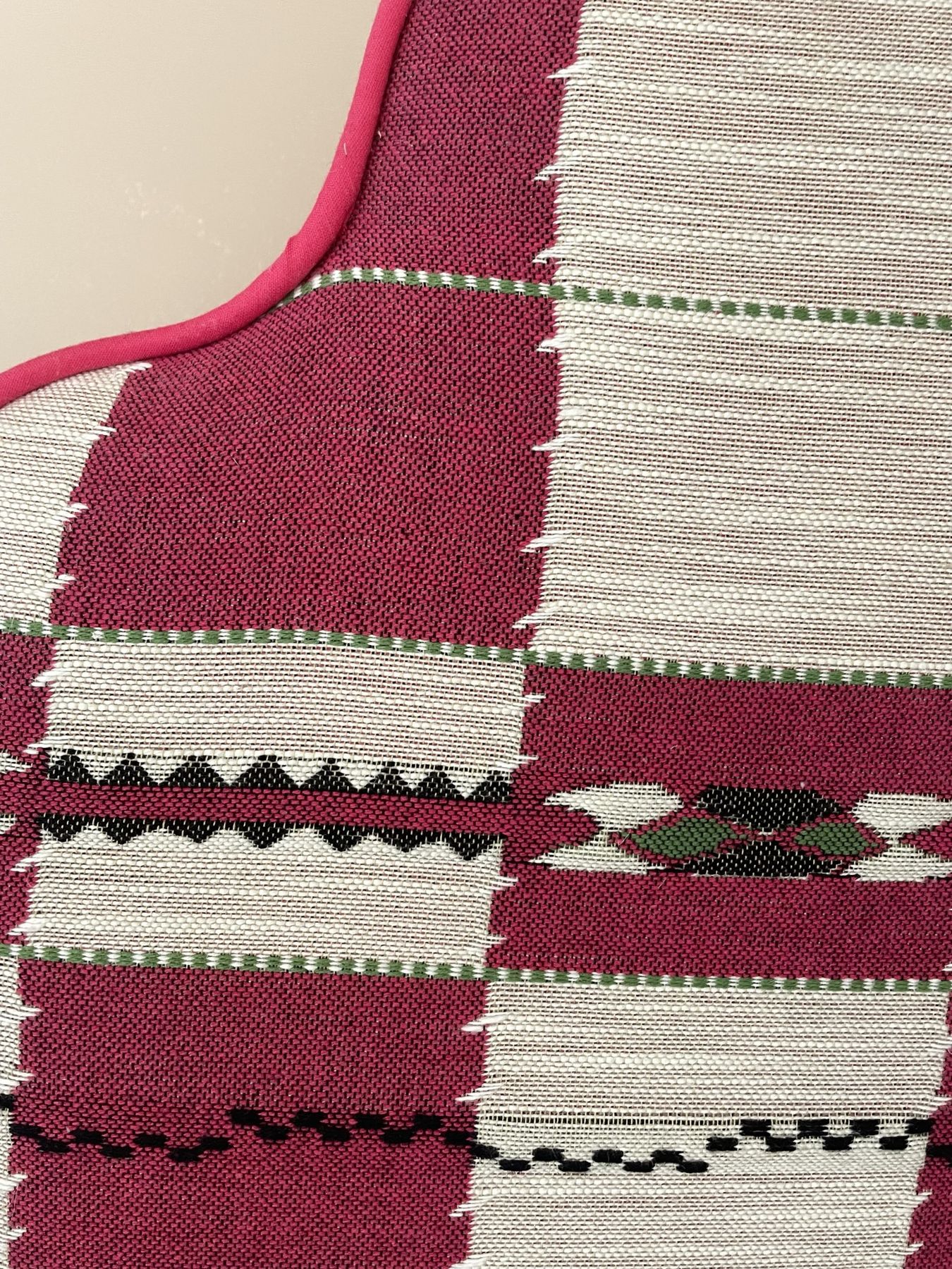 Close-up of the woven headboard fabric in red, cream, green and black