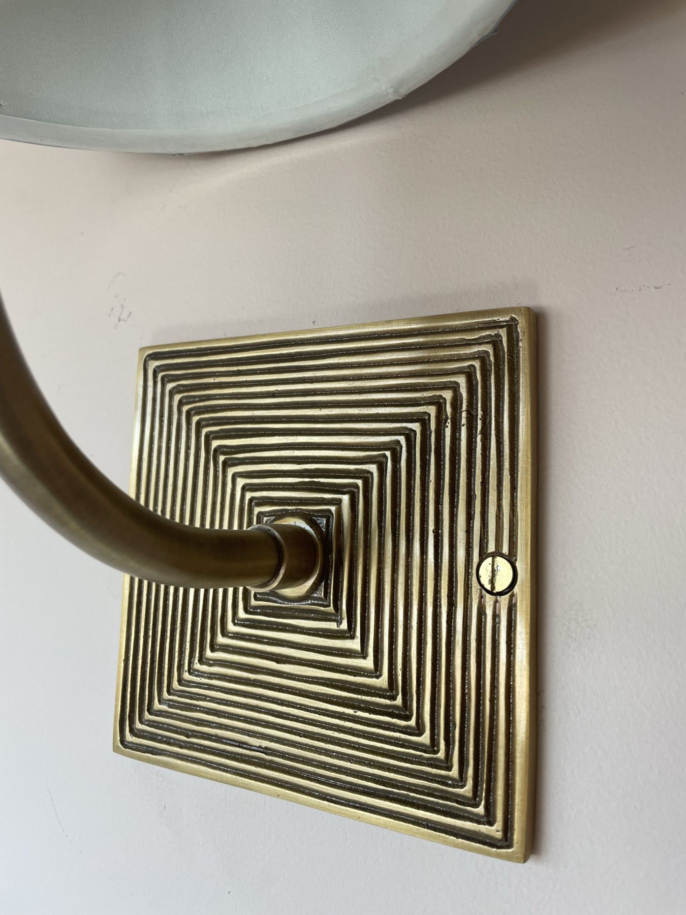 A brass wall light backplate with a ridged square design