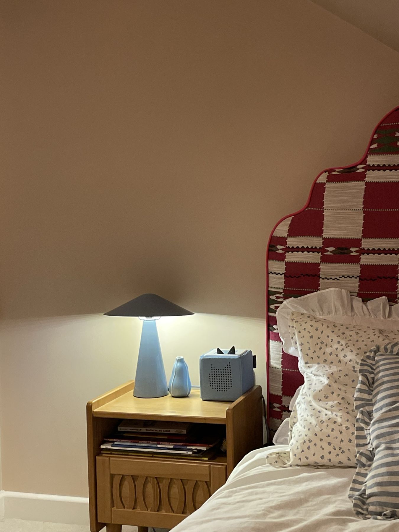 A blue lamp on a wooden bedside table beside the headboard