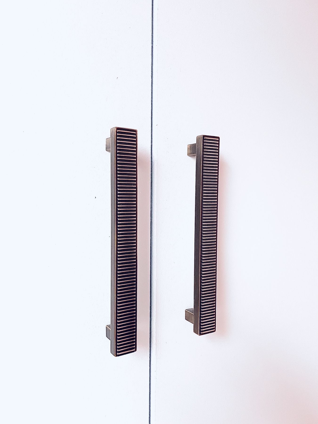 Dark ribbed handles on pale grey wardrobe doors