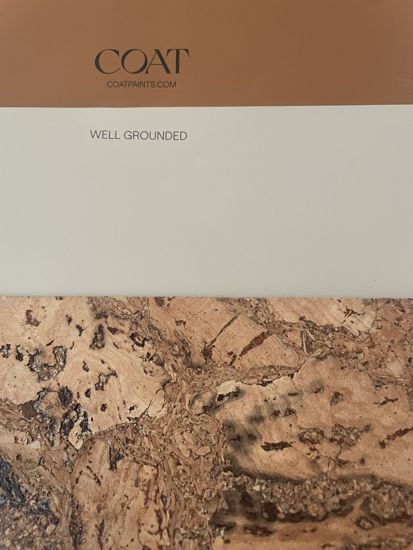 A cork wallcovering sample beside a terracotta paint swatch
