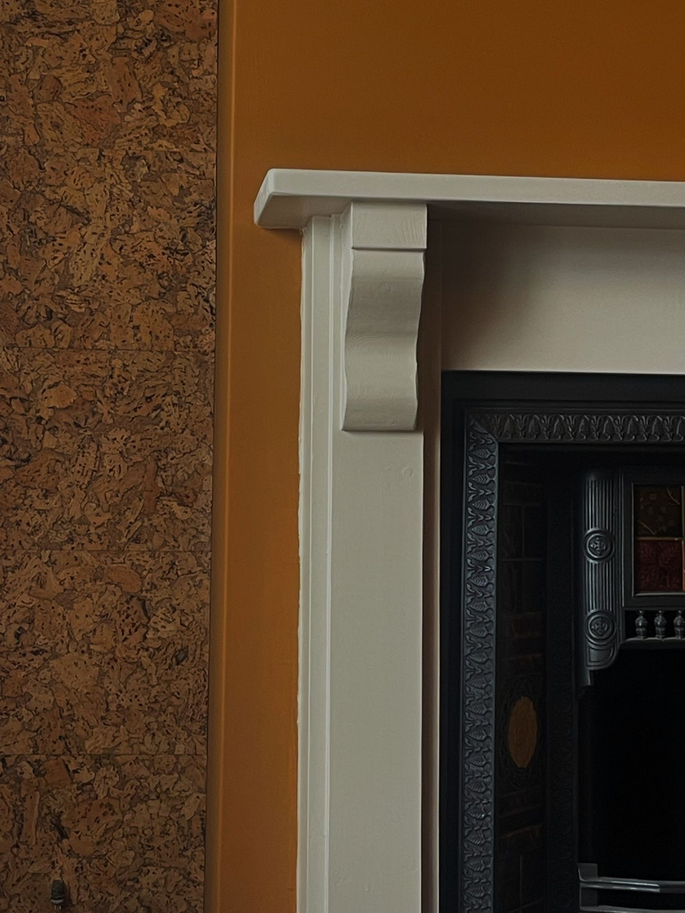 A cream fire surround beside a cork-lined alcove and terracotta wall