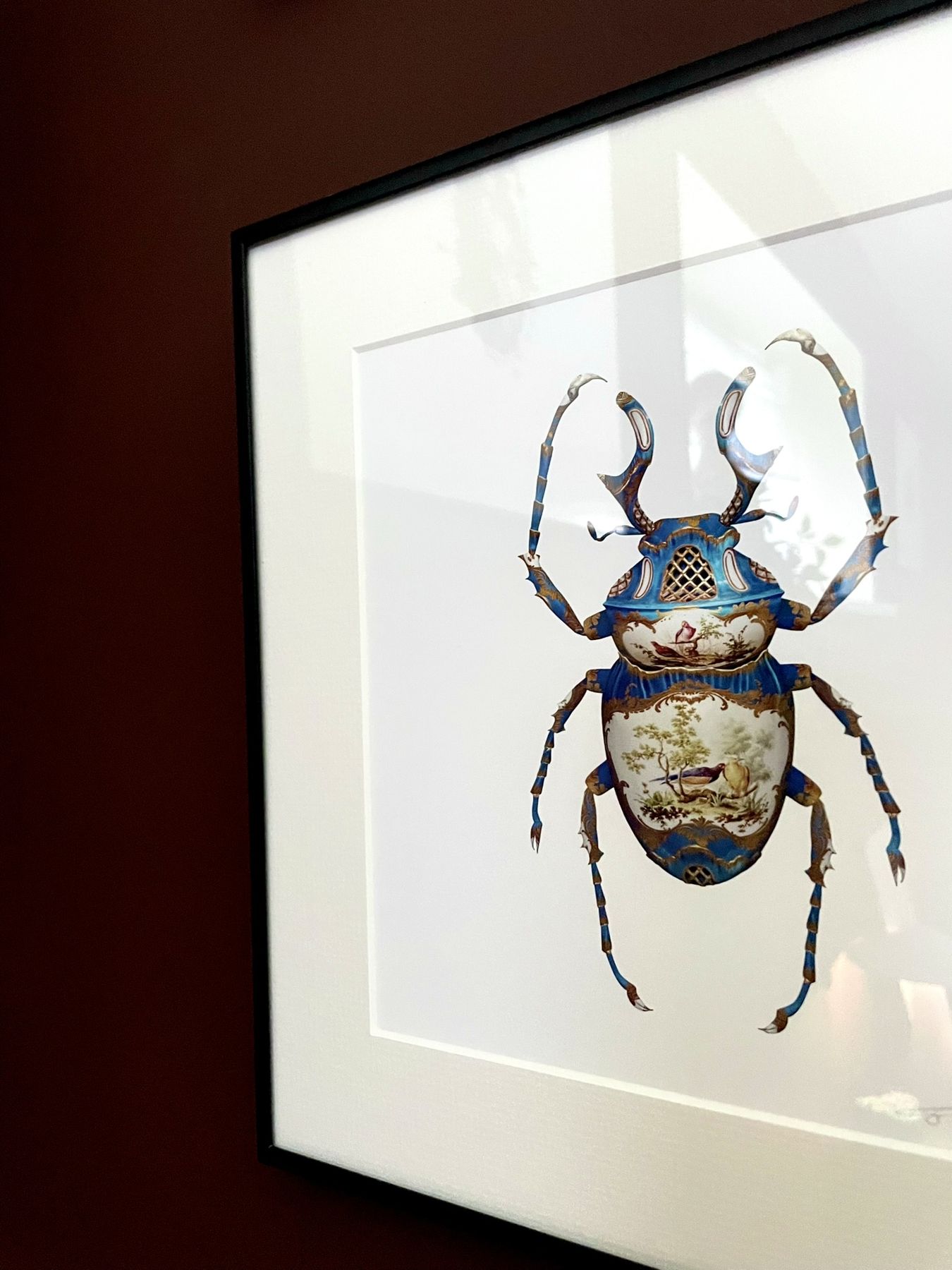A framed illustration of an iridescent beetle on a plum wall