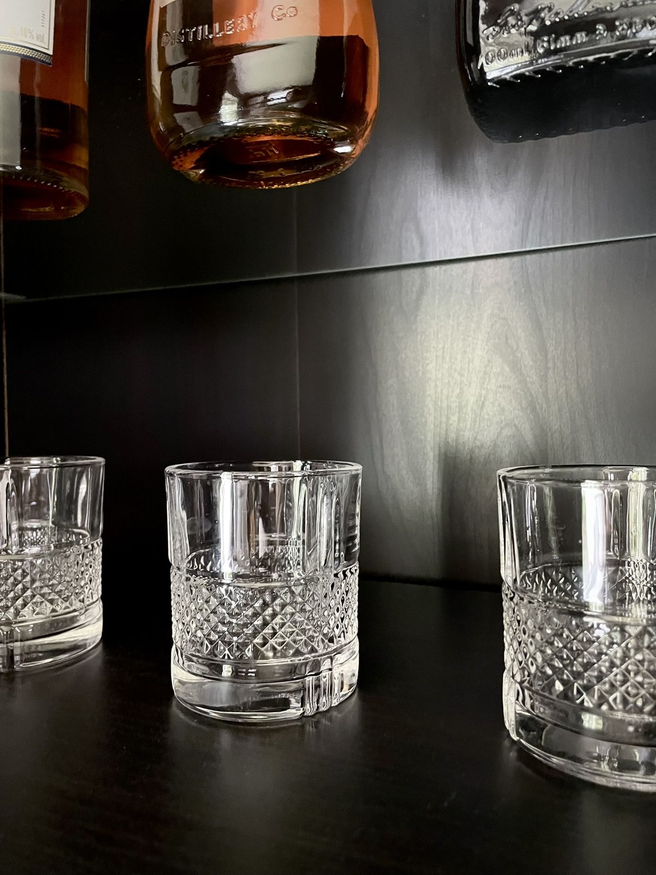 Cut-glass tumblers and a decanter on a dark wooden shelf