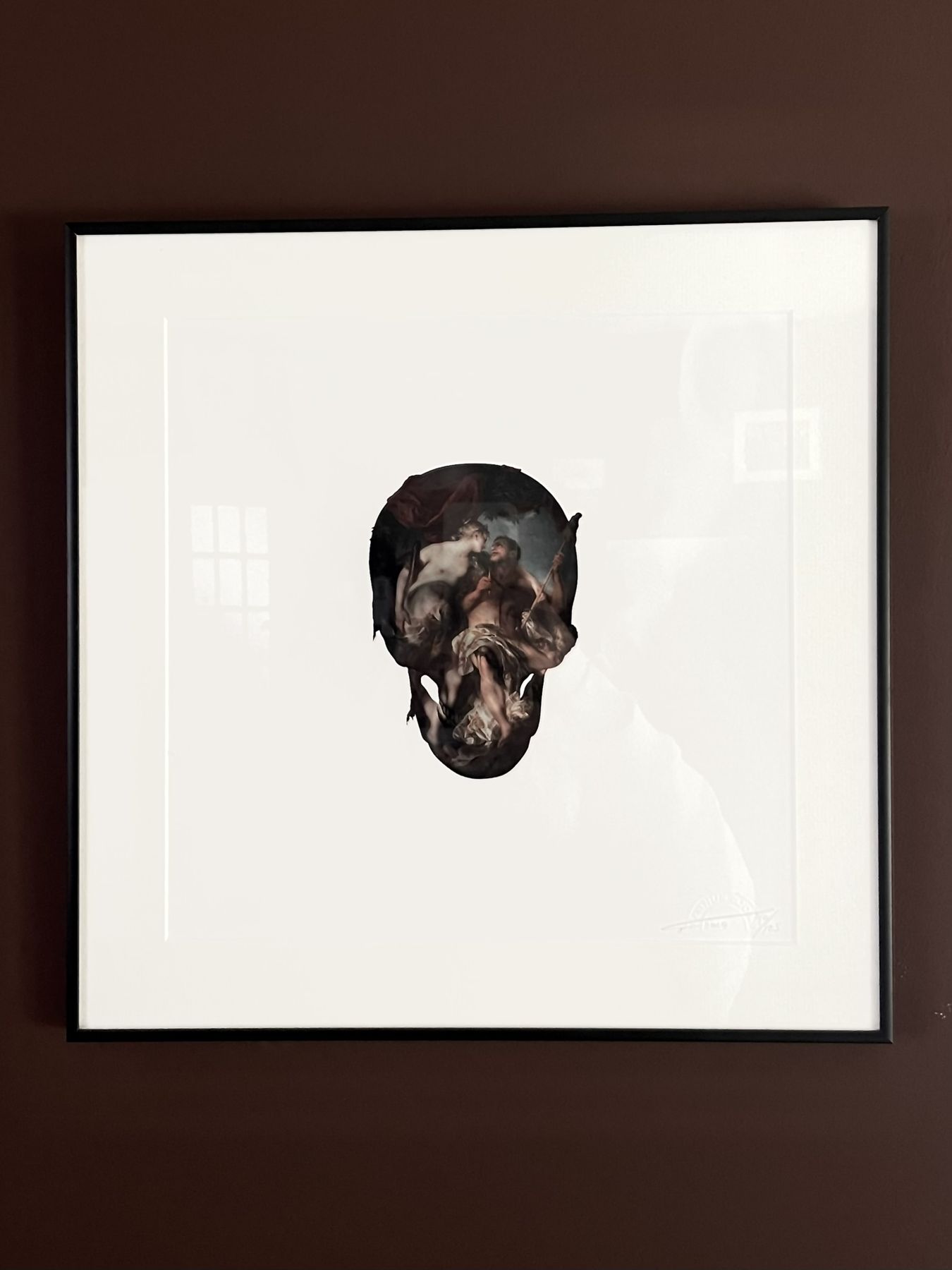 A framed print of a dark mammal skull on a plum wall