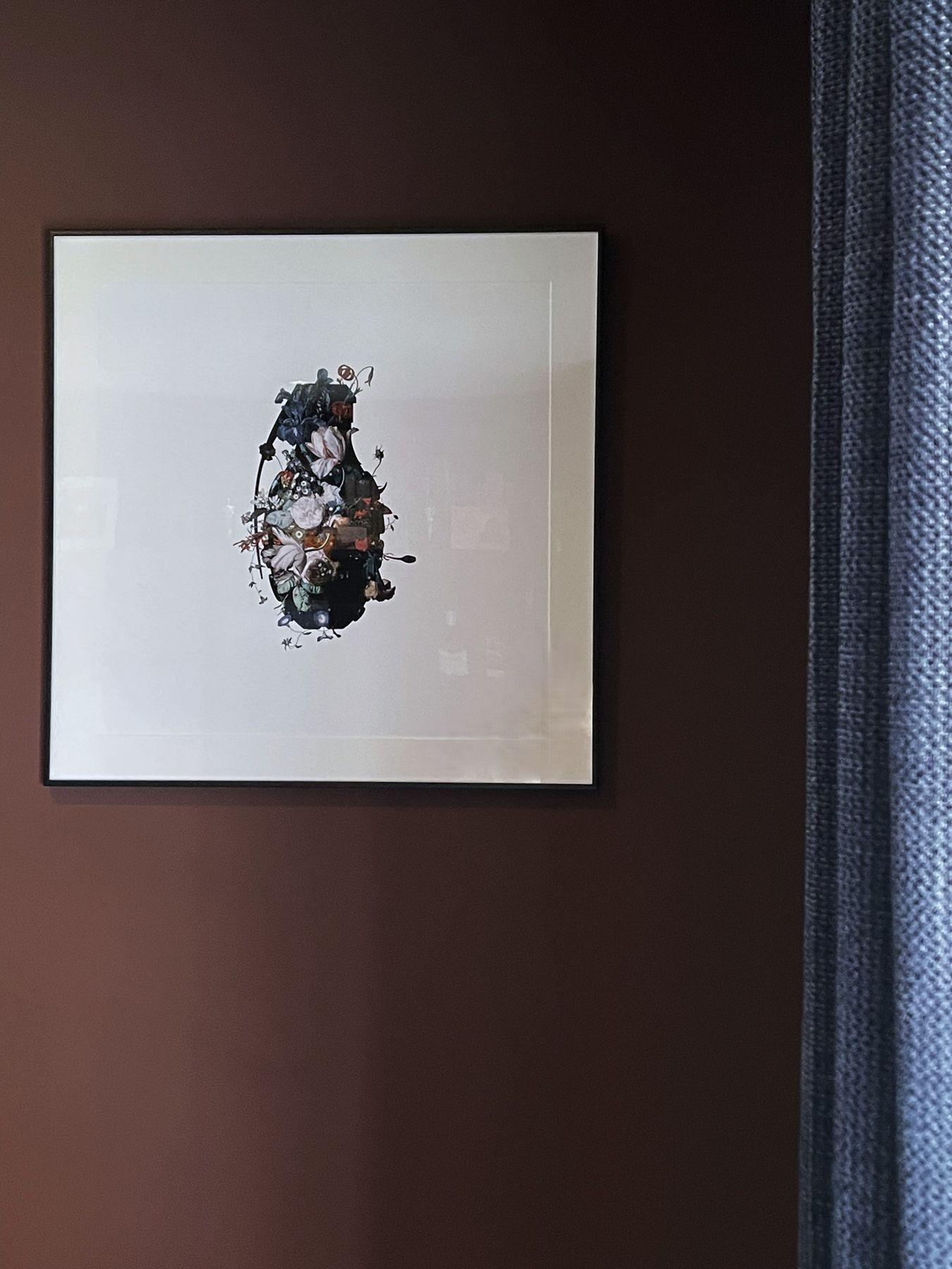 A framed abstract ink print by a navy curtain