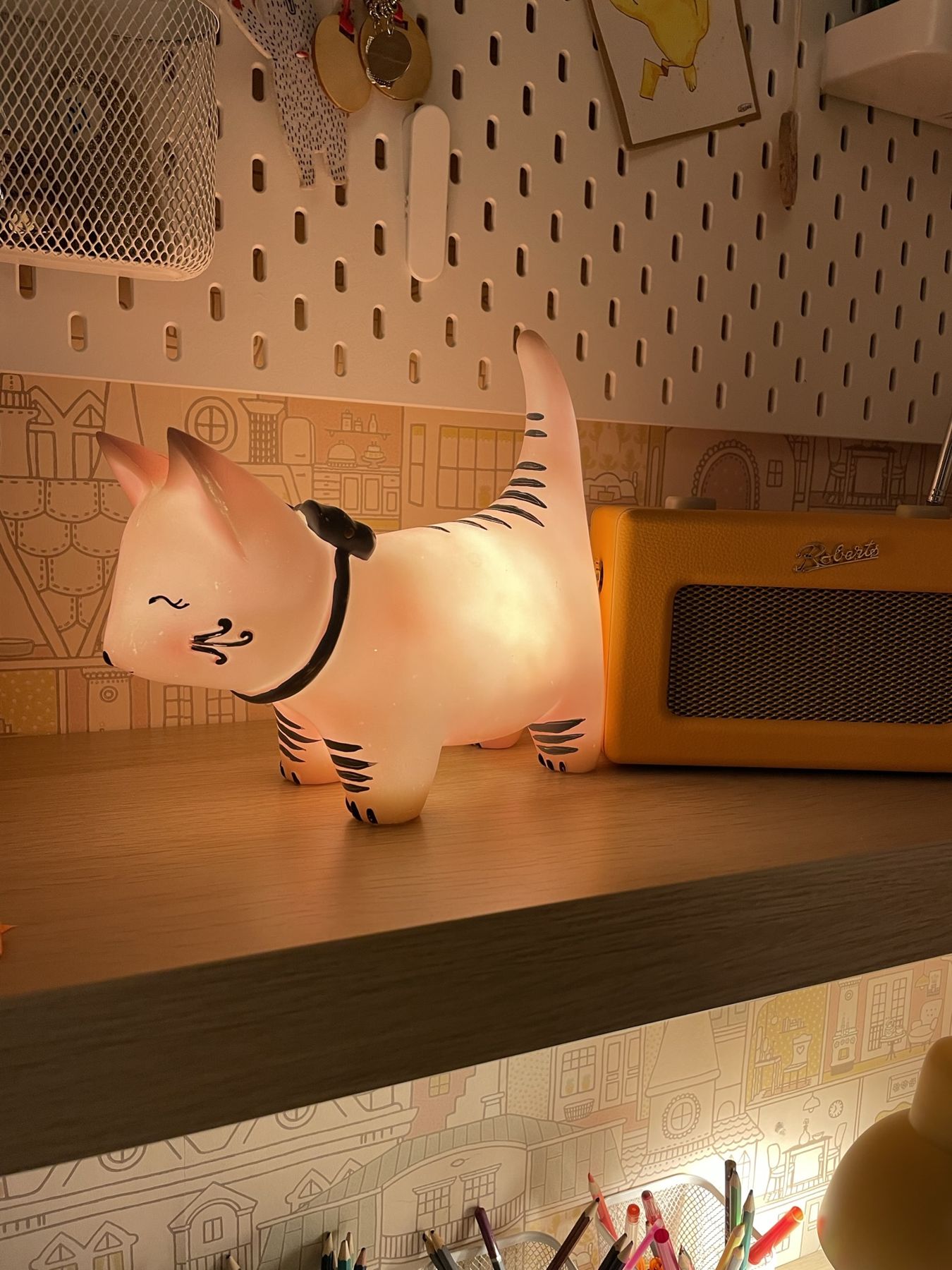 A cat-shaped night light on a shelf beside a pegboard