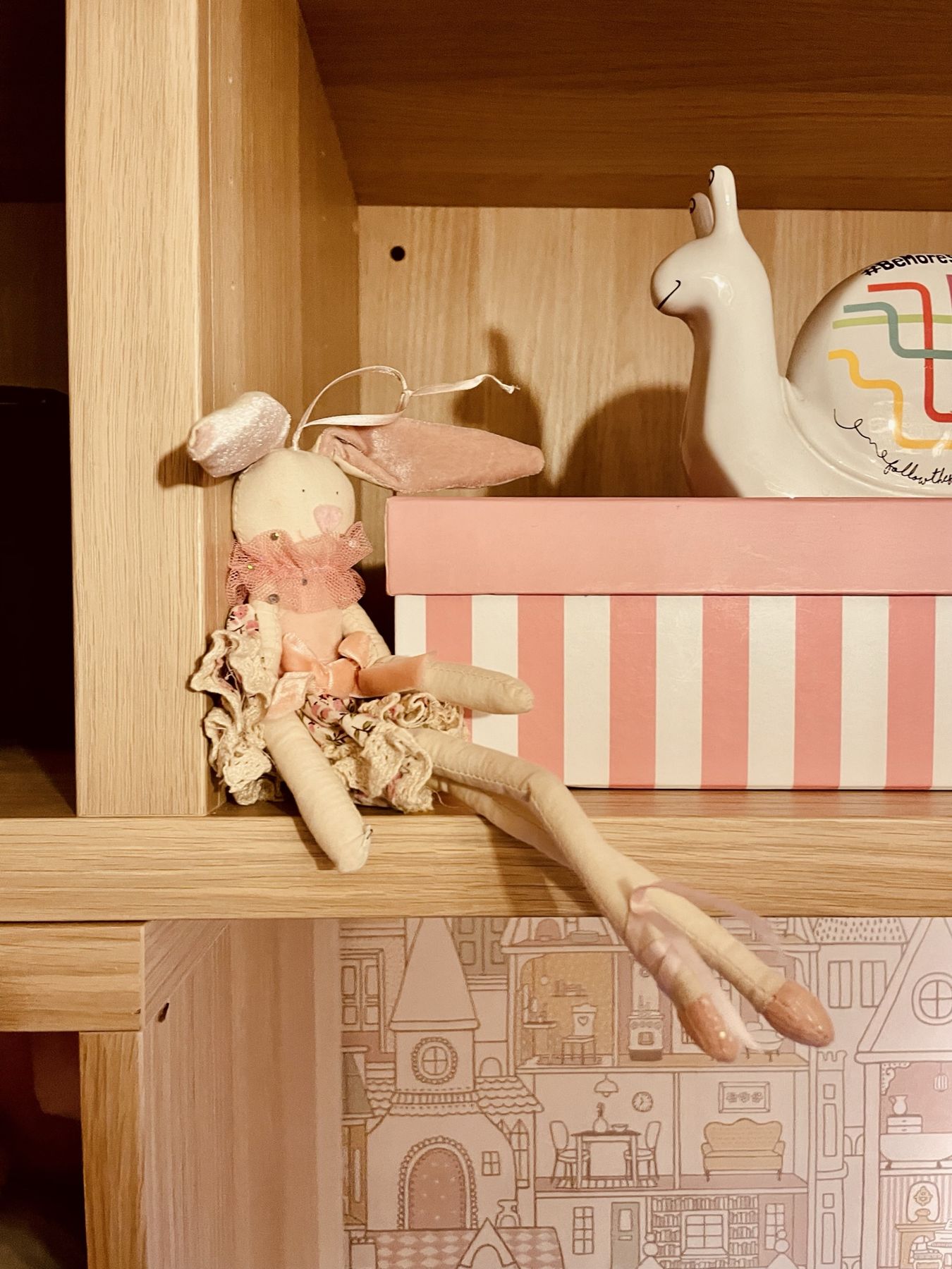 A rag doll and llama ornament on a shelf with a striped box