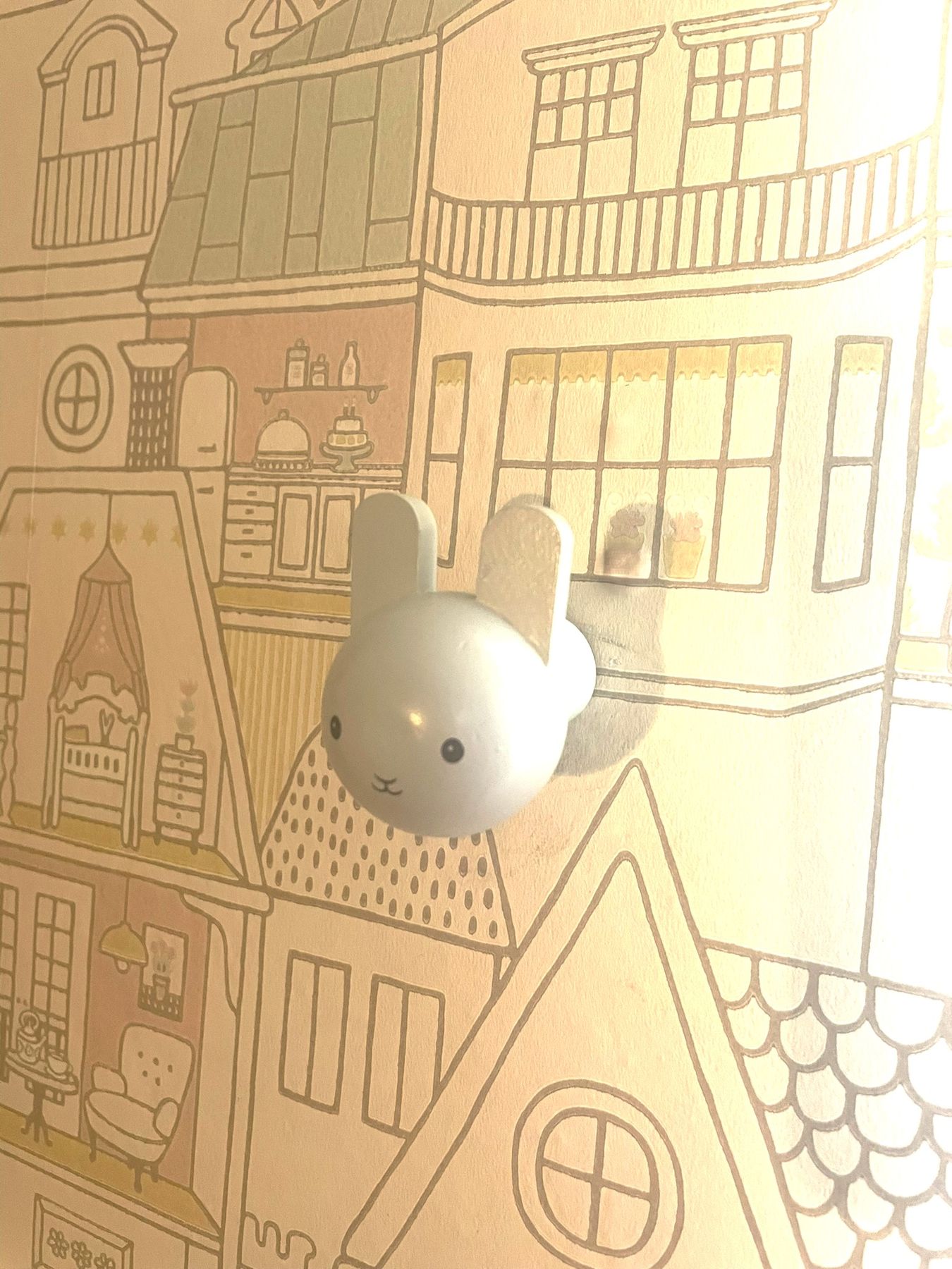 A white bunny-head wall hook on townhouse wallpaper