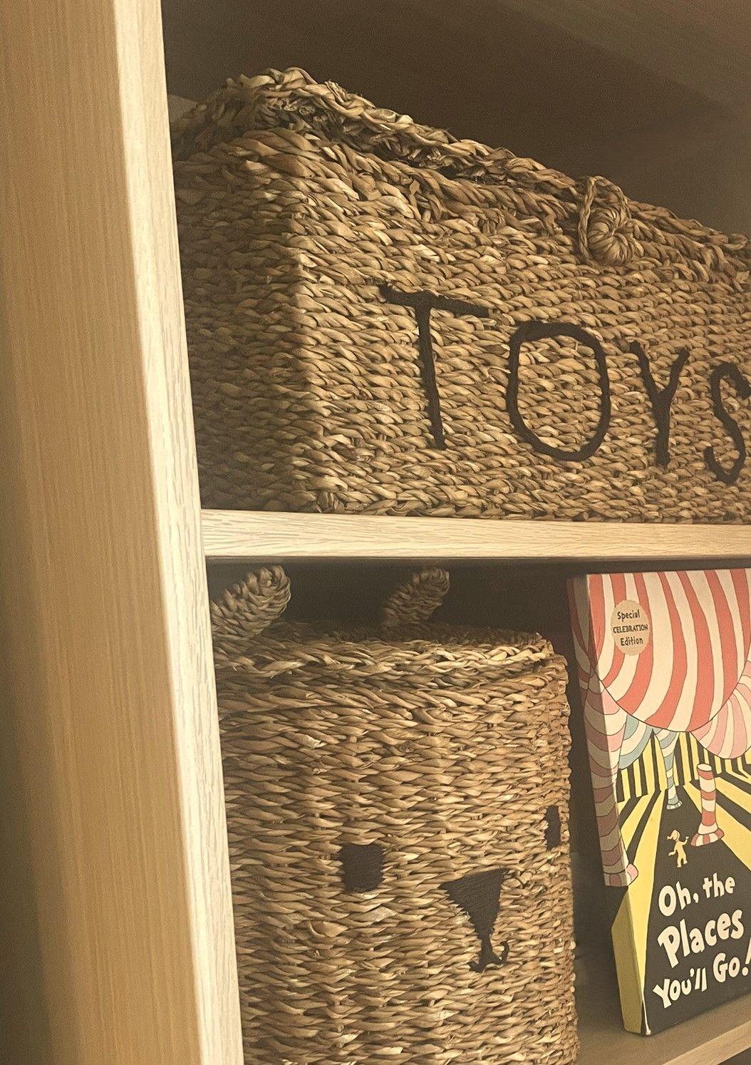Seagrass storage baskets marked TOYS in pale wood shelving