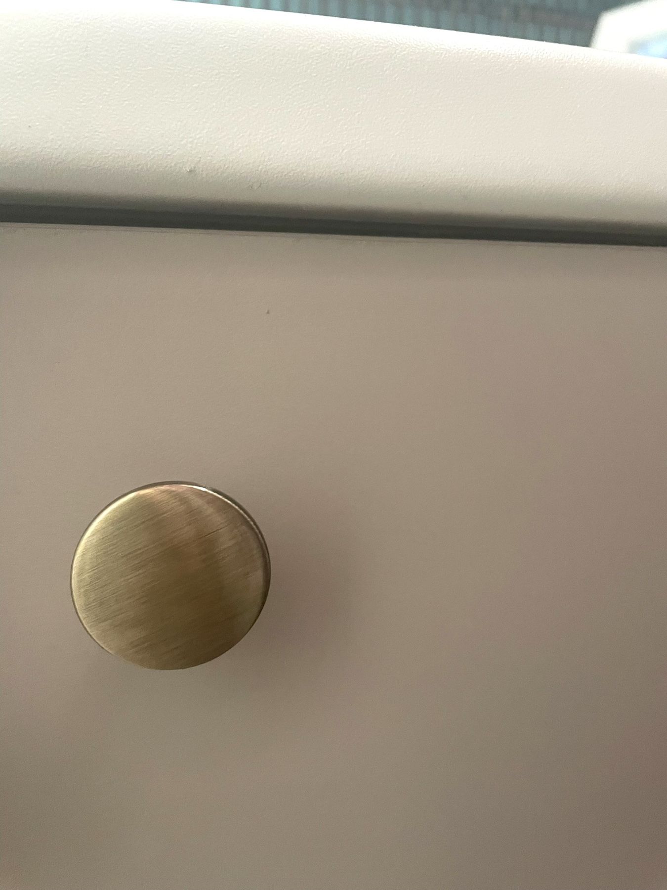 A round brass knob on a cream cabinet door