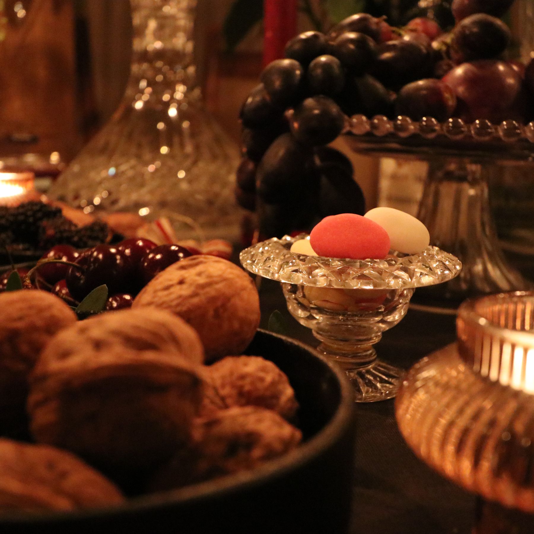 Sugared almonds in a cut-glass dish beside walnuts